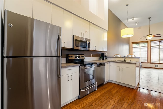 kitchen with white cabinetry, stainless steel appliances, kitchen peninsula, ceiling fan, and sink