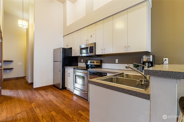 kitchen featuring light wood-type flooring, stainless steel appliances, sink, kitchen peninsula, and white cabinets