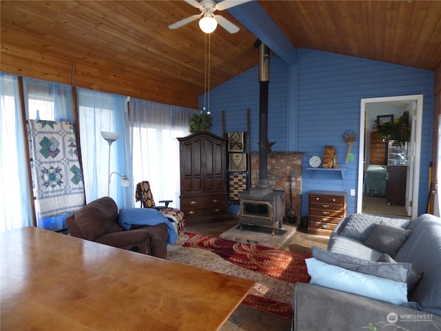 living room featuring lofted ceiling with beams, a wood stove, a healthy amount of sunlight, and ceiling fan