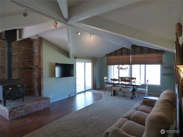 living room featuring lofted ceiling with beams, a healthy amount of sunlight, wood-type flooring, and a wood stove