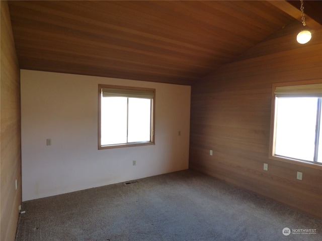 empty room featuring vaulted ceiling, a healthy amount of sunlight, wood ceiling, and carpet floors