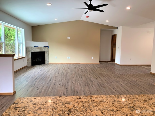 unfurnished living room featuring a tiled fireplace, wood-type flooring, ceiling fan, and vaulted ceiling