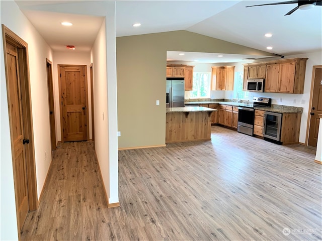 kitchen featuring appliances with stainless steel finishes, light stone counters, wine cooler, light wood-type flooring, and ceiling fan