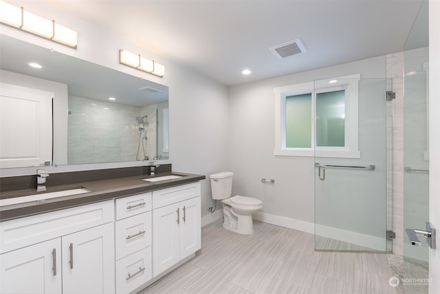 bathroom featuring walk in shower, toilet, dual sinks, and vanity with extensive cabinet space