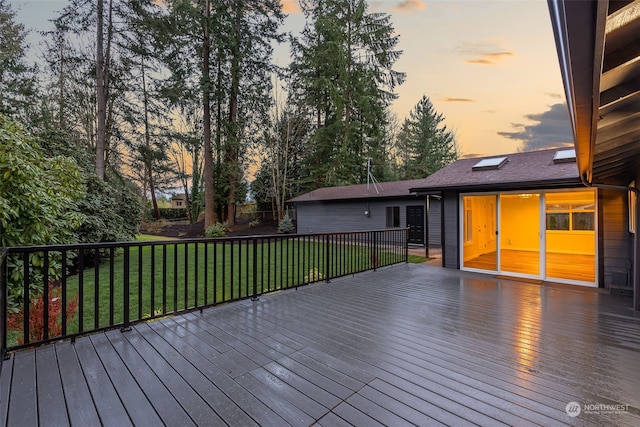 deck at dusk featuring a lawn