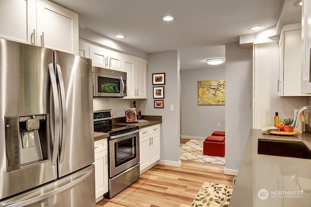 kitchen featuring white cabinets, light hardwood / wood-style flooring, sink, and stainless steel appliances