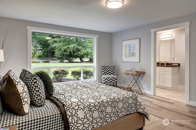 bedroom featuring sink, ensuite bathroom, and light wood-type flooring