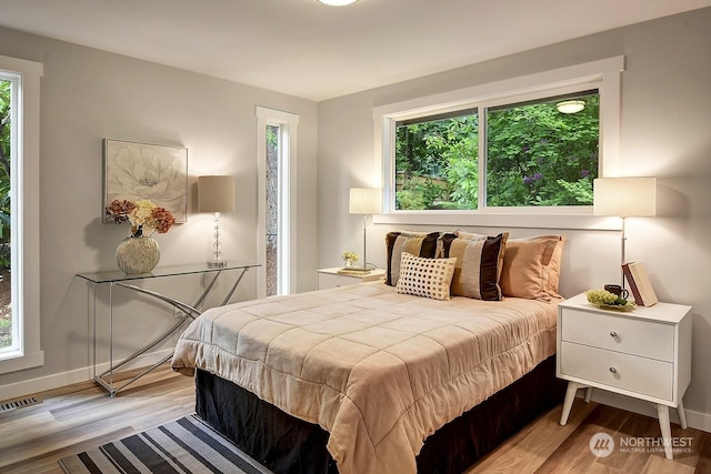 bedroom with multiple windows and light hardwood / wood-style floors