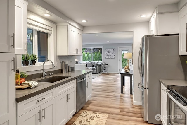 kitchen featuring appliances with stainless steel finishes, light hardwood / wood-style floors, white cabinetry, and sink