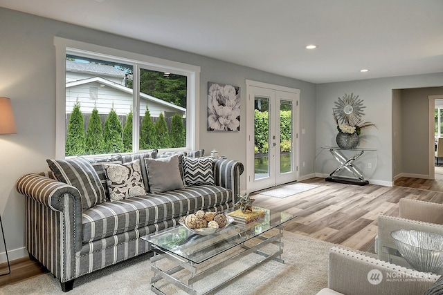 living room with plenty of natural light, french doors, and light hardwood / wood-style floors