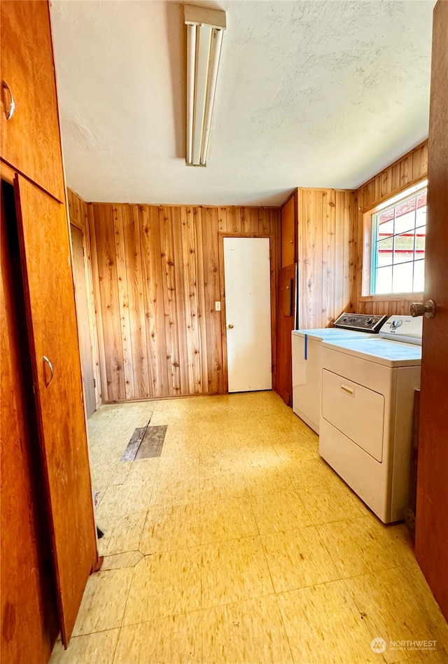 laundry room featuring light tile flooring, wood walls, and washing machine and dryer