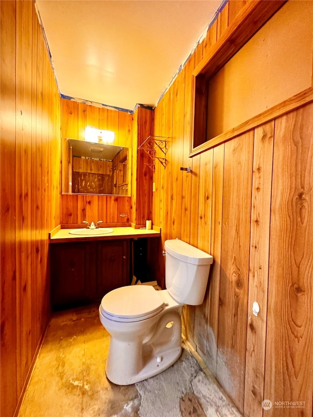 bathroom featuring wood walls, toilet, and vanity