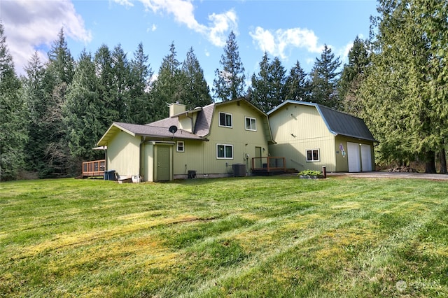 back of property featuring a deck, a yard, and a garage