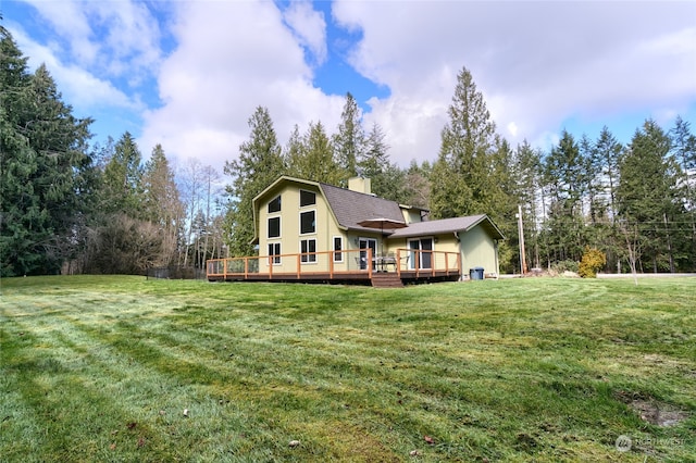 rear view of property featuring a wooden deck and a yard