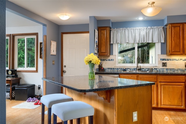 kitchen featuring dark stone countertops, backsplash, and light hardwood / wood-style flooring