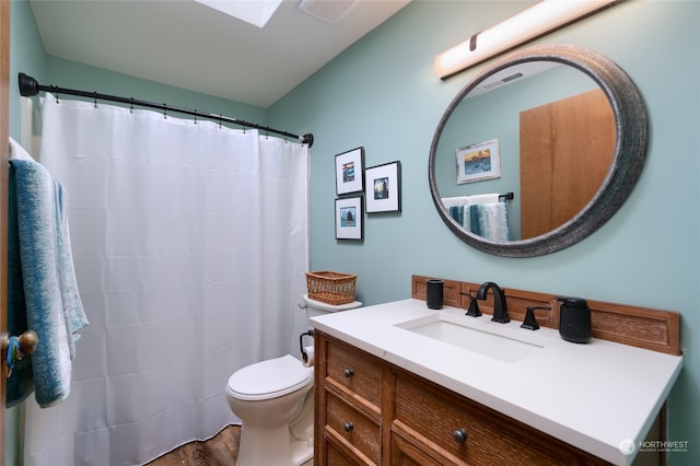 bathroom featuring toilet, a skylight, large vanity, and hardwood / wood-style flooring