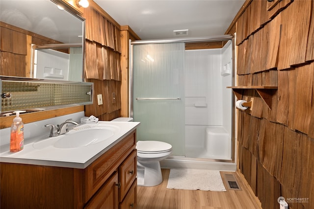 bathroom with vanity, hardwood / wood-style floors, backsplash, a shower with door, and toilet