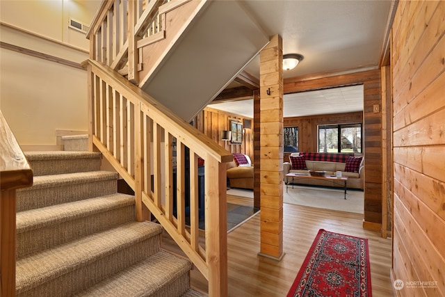 stairs featuring wooden walls and light hardwood / wood-style floors