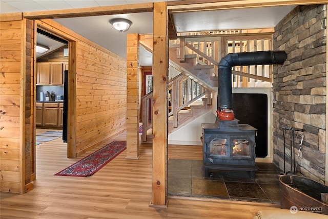 interior space with a wood stove, light wood-type flooring, and wooden walls