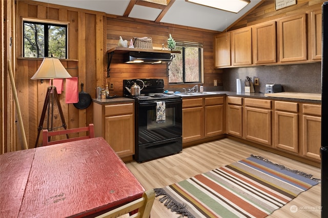 kitchen with lofted ceiling, black / electric stove, sink, light hardwood / wood-style flooring, and wood walls