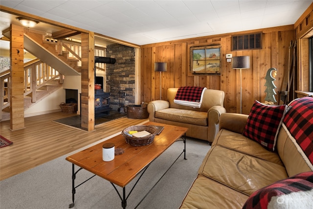 living room featuring wooden walls, a wood stove, and light wood-type flooring