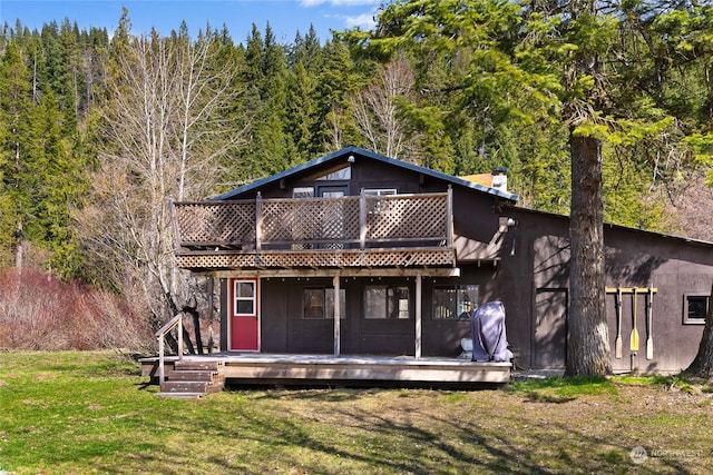 back of property with a balcony, a deck, and a yard