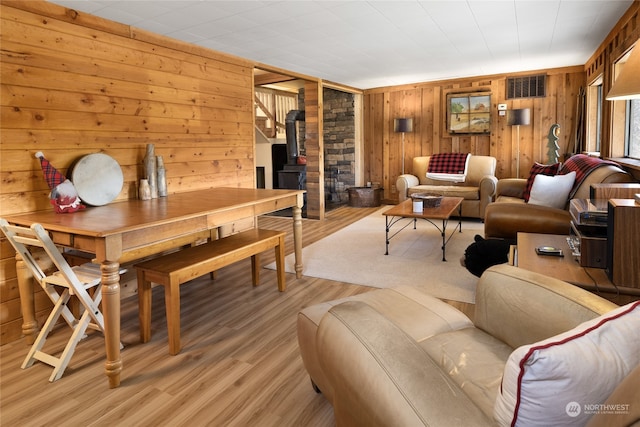 interior space with wood walls, a wood stove, and light wood-type flooring