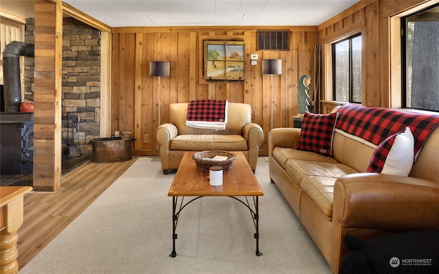 living room featuring wooden walls, a wood stove, and light wood-type flooring