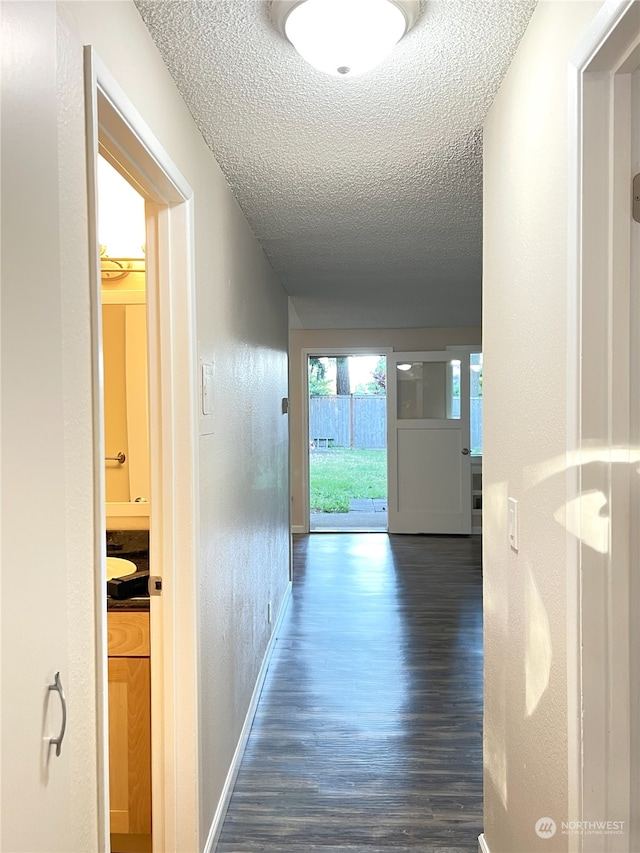 hall featuring a textured ceiling and dark hardwood / wood-style flooring