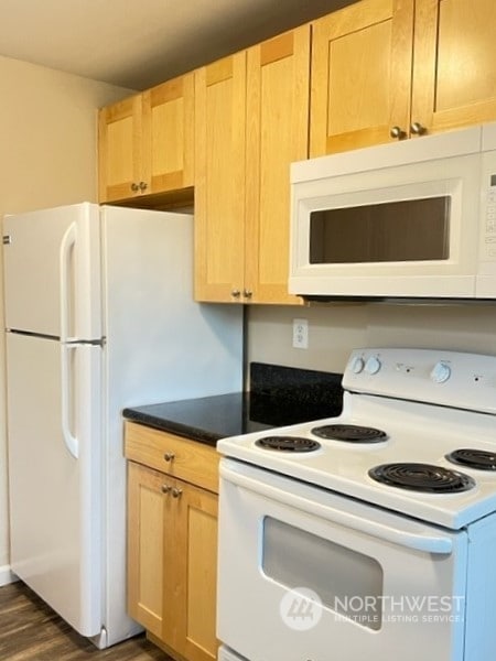 kitchen featuring light brown cabinetry, white appliances, and dark wood-type flooring