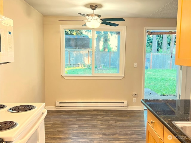 kitchen featuring dark hardwood / wood-style flooring, dark stone counters, baseboard heating, ceiling fan, and white appliances