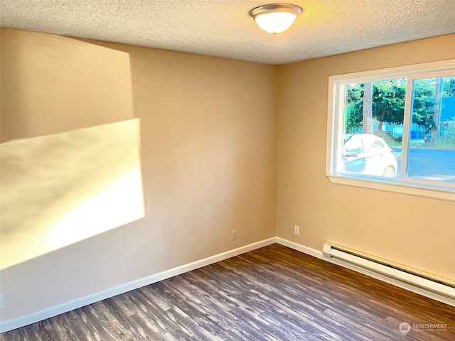 spare room featuring baseboard heating, dark wood-type flooring, and a textured ceiling