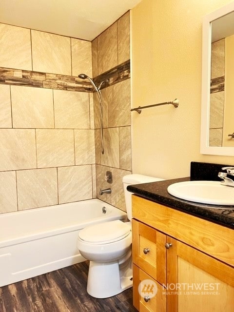 full bathroom with toilet, hardwood / wood-style floors, oversized vanity, and tiled shower / bath