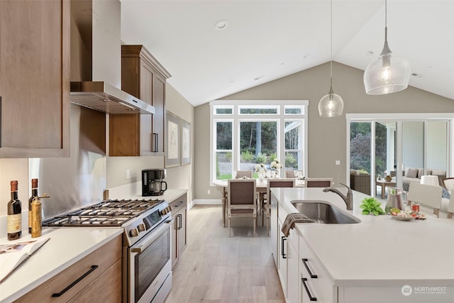 kitchen with stainless steel range, hanging light fixtures, wall chimney exhaust hood, and vaulted ceiling