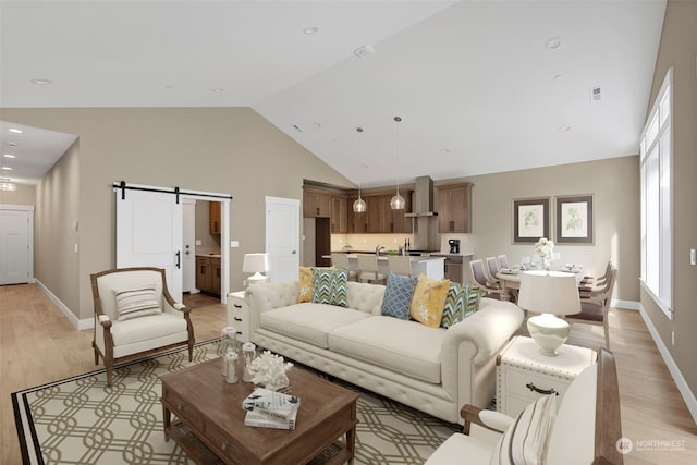 living room with a barn door, high vaulted ceiling, and light hardwood / wood-style flooring