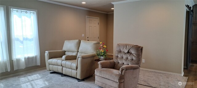 living area with a barn door, ornamental molding, and light wood-type flooring