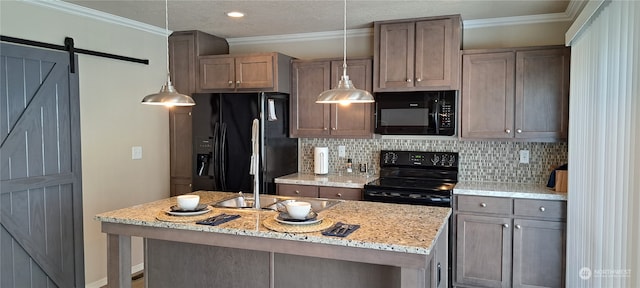 kitchen featuring light stone countertops, backsplash, black appliances, a barn door, and an island with sink