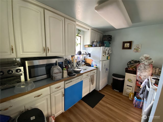 kitchen featuring white appliances, light wood-type flooring, and white cabinets