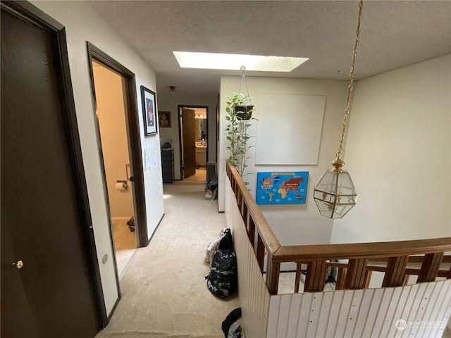 hall with a textured ceiling, light carpet, and a skylight