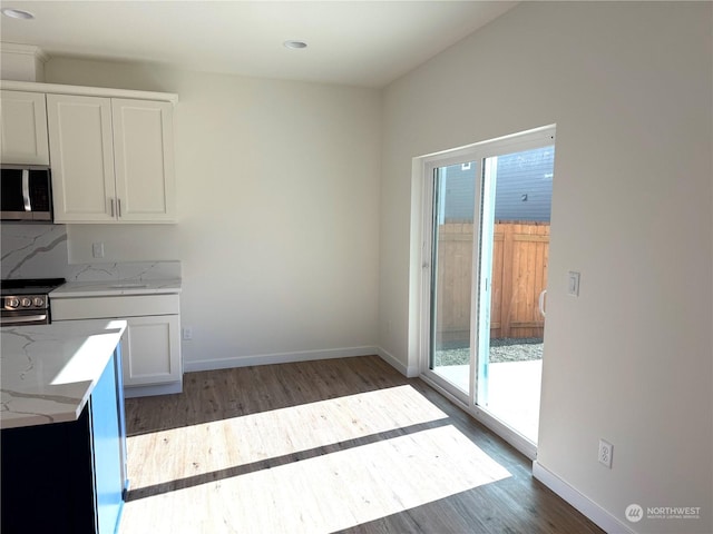 kitchen featuring decorative backsplash, appliances with stainless steel finishes, light stone countertops, white cabinets, and dark hardwood / wood-style floors