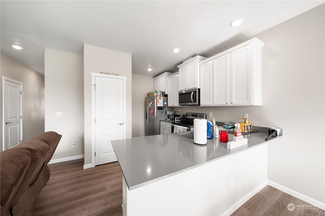 kitchen with white cabinets, kitchen peninsula, dark wood-type flooring, and appliances with stainless steel finishes