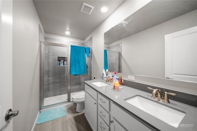 bathroom featuring walk in shower, tile floors, toilet, and dual bowl vanity