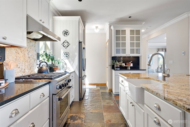 kitchen with tasteful backsplash, dark tile floors, stainless steel appliances, and light stone countertops