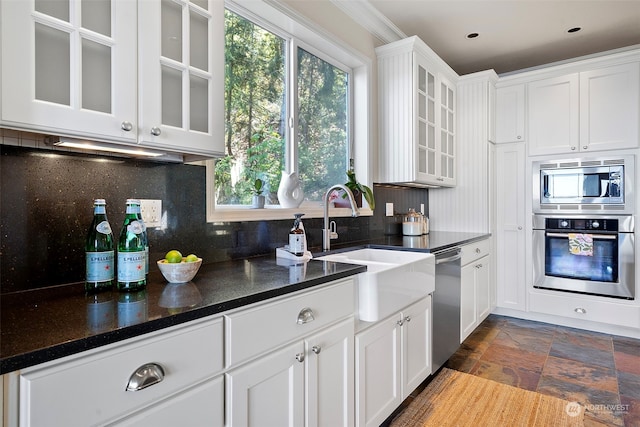 kitchen featuring appliances with stainless steel finishes, crown molding, tasteful backsplash, dark tile flooring, and white cabinets