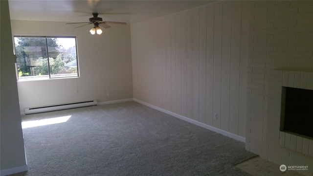 carpeted empty room featuring a brick fireplace, wooden walls, ceiling fan, and baseboard heating