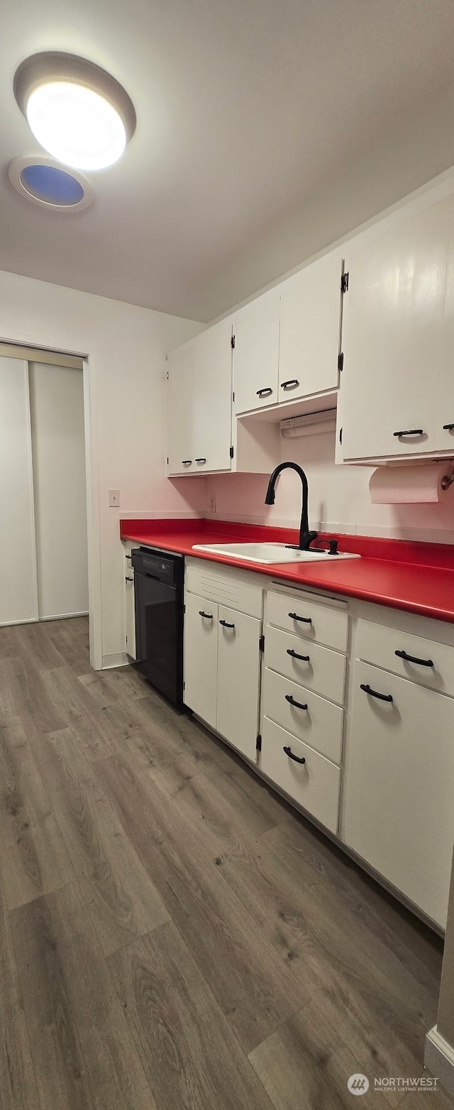 kitchen featuring dark hardwood / wood-style flooring, dishwasher, sink, and white cabinets