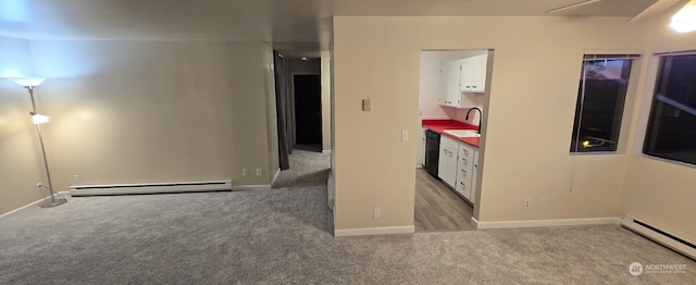 carpeted spare room featuring a baseboard radiator and sink