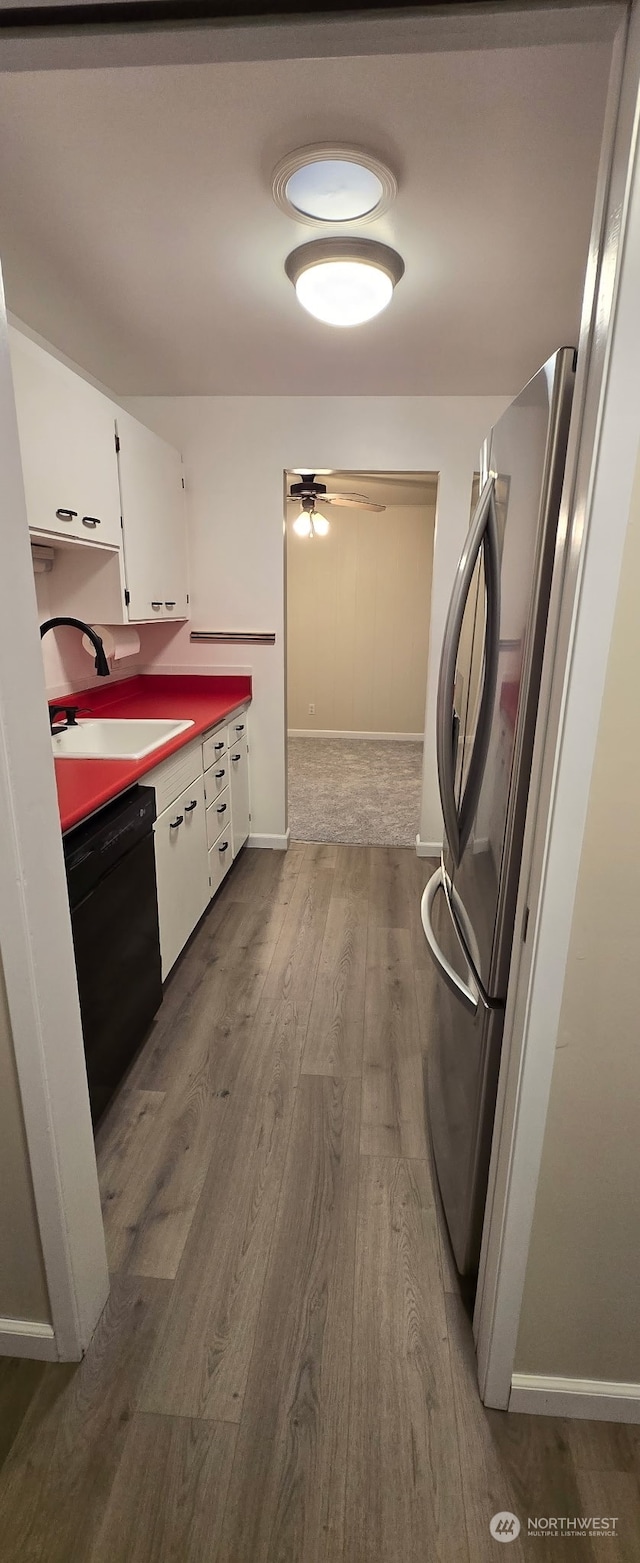 kitchen featuring dishwasher, sink, stainless steel fridge, white cabinets, and light hardwood / wood-style flooring