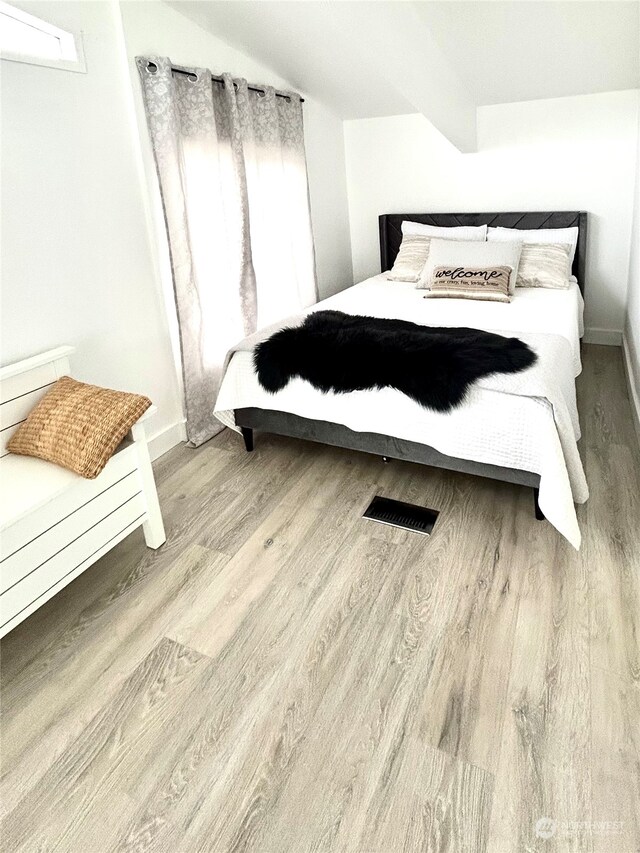 bedroom featuring beamed ceiling and light hardwood / wood-style floors