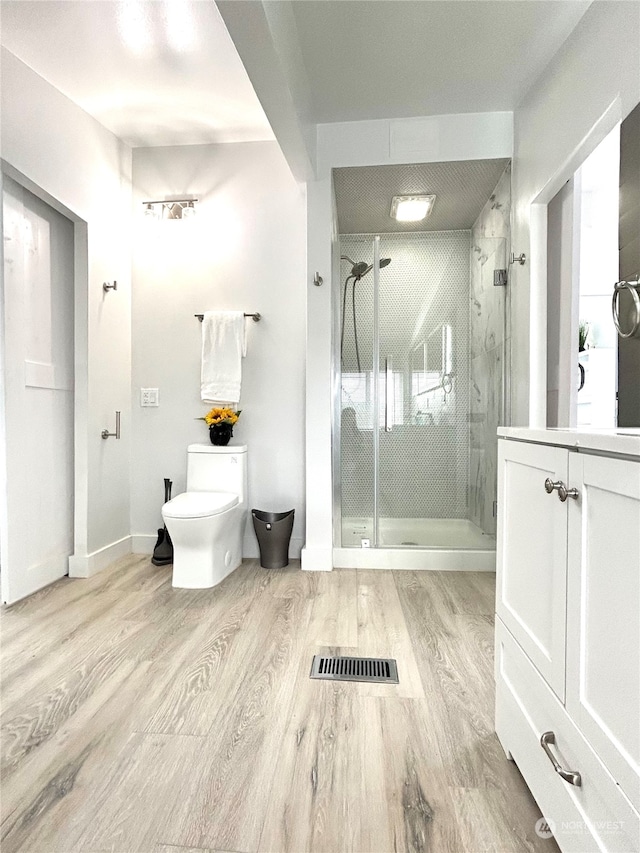 bathroom featuring vanity, hardwood / wood-style flooring, toilet, and walk in shower